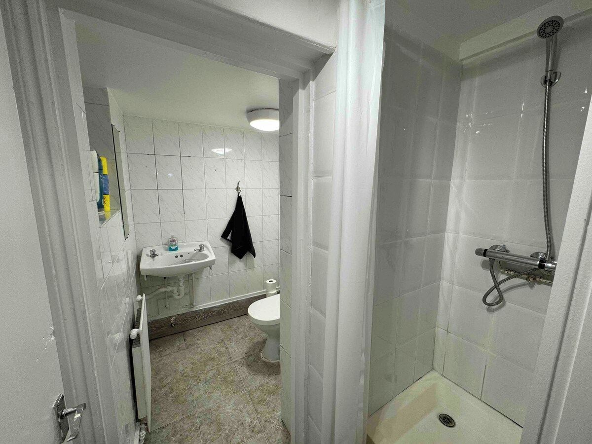 A bathroom with a shower, toilet, sink, and a towel hanging on the wall.