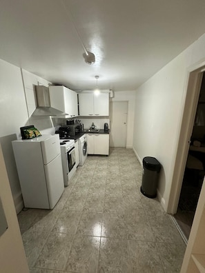 A compact kitchen with white cabinets, a refrigerator, a stove, and a washing machine. - Apartment - Heart of London! (Greater London)