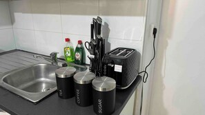 Eine Küchenarbeitsplatte mit Spüle, Toaster und drei Behältern, beschriftet mit Tee, Kaffee und Zucker.