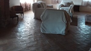 Een woonkamer met een stenen vloer, een open haard en een kroonluchter.