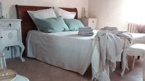 Een slaapkamer met een bed, nachtkastjes, een stoel en een dressoir.
