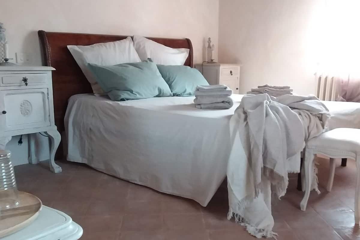 Een slaapkamer met een bed, nachtkastjes, een stoel en een dressoir.