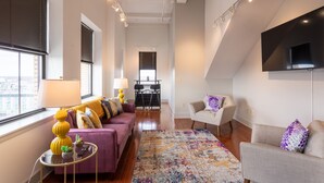 A modern living room with a sofa, armchairs, a coffee table, and a TV mounted on the wall. - Skyline Square  (Niagara Falls)