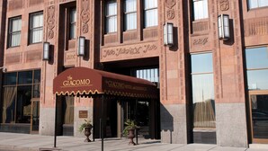 A historic building with a large entrance, ornate brickwork, and a sign reading "The Giacomo Hotel and Residences." - Skyline Square  (Niagara Falls)
