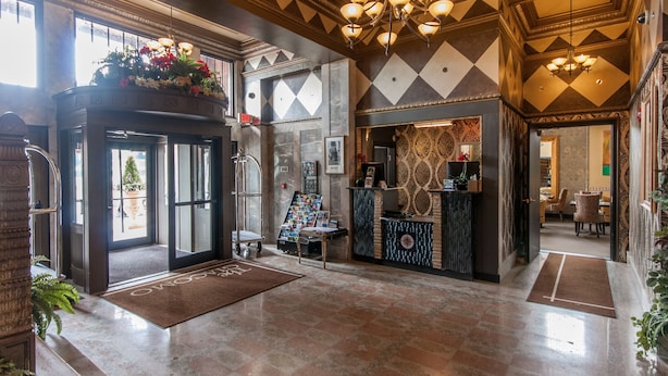 A lobby with a reception desk, a large chandelier, and a patterned wall. - Skyline Square  (Niagara Falls)
