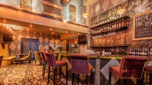A bar area with patterned carpet, bar stools, and a wine rack. - Skyline Square  (Niagara Falls)
