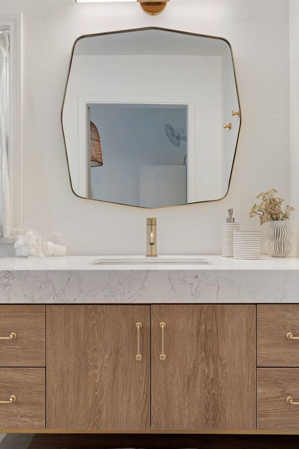 Une salle de bain avec un grand miroir, un robinet doré et des meubles en bois.