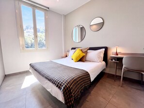 Un dormitorio moderno con una cama grande, dos espejos en las mesitas de noche, un escritorio y una silla.