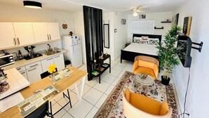 Een ruimtelijke leefruimte met keuken, eetgedeelte en slaapkamer.