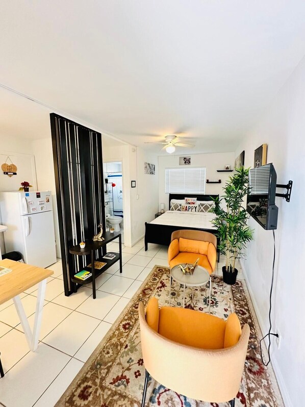 Un espacio habitable compacto con cama, sofá, mesa de comedor y zona de cocina.