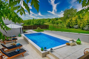 Relax by the pool surrounded by lush greenery and trees.