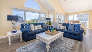 Un salon spacieux avec un canapé d’angle bleu foncé, une table basse blanche et un tapis à motifs.