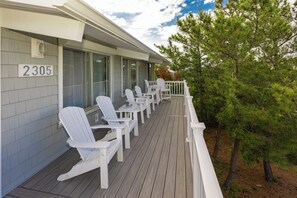 A wooden deck with white Adirondack chairs, a white railing, and a number sign '2305' on the building. - Brownley Beach Cottage- steps to the Beach, Elevator, Dog Friendly! (Virginia Beach)