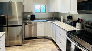 Una cocina moderna con techo de madera, electrodomésticos de acero inoxidable y armarios blancos.