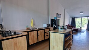 Una cocina moderna con armarios de madera, una estufa a gas y un lavamanos. Hay una zona de comedor con un sofá y una mesa.