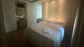 Een hotelkamer met een bed, een bureau en een kledingkast.