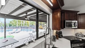 Une cuisine moderne dotée d’une grande fenêtre donnant sur un espace piscine.