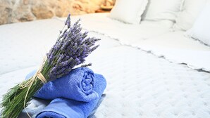 A room with stone walls, a bed with white bedding, and a lavender bouquet on the bed. - Secluded and Peaceful Retreat House on the Island of Hvar (Velo Grablje)
