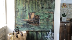 A rustic wooden wall with a wooden coat rack, a woven basket, and a small wooden cabinet with a vase and a candle. - Secluded and Peaceful Retreat House on the Island of Hvar (Velo Grablje)