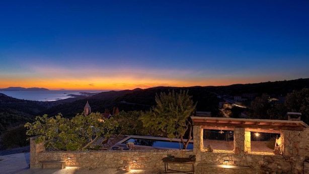 A stone building with a pool and outdoor seating, overlooking a coastal landscape at sunset. - Secluded and Peaceful Retreat House on the Island of Hvar (Velo Grablje)