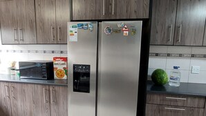 A kitchen with two stainless steel refrigerators, wooden cabinets, a microwave, and a water dispenser on the countertop. - A staycation in walvis bay
 (walvis bay)