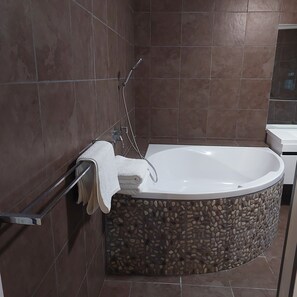 A modern bathroom with a freestanding bathtub, a towel rack, and a shower head.