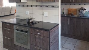 A modern kitchen with dark wood cabinetry, a stainless steel stove, and a tiled backsplash. - A staycation in walvis bay
 (walvis bay)
