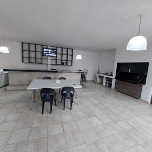 Eine moderne Küche mit Essbereich, einem an der Wand montierten Fernseher und einem großen Fernseher an der Wand.
