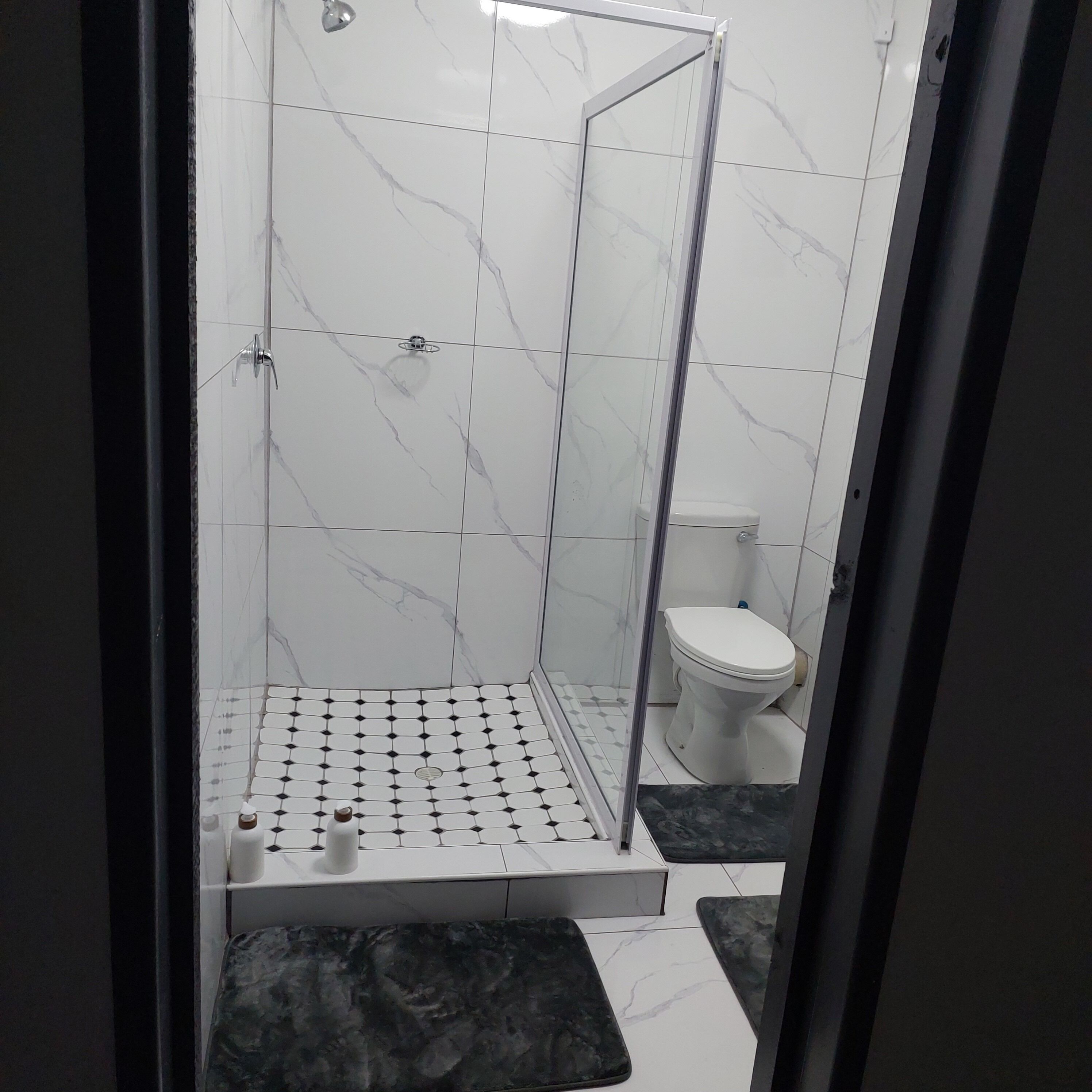 Un baño moderno con ducha de vidrio, inodoro y piso estampado.
