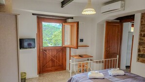 Een slaapkamer met een bed, een houten deur, een tafeltje, een televisie en een airconditioning.