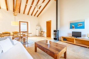 Cozy living area with a high ceiling, wood-burning stove, and comfortable seating.
