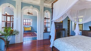 Ein Schlafzimmer mit einem Himmelbett, Holzboden und einem großen Fenster mit Vorhängen.