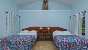 A bedroom with two beds, a wooden headboard, two bedside tables with lamps, and a ceiling fan.