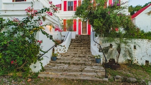 Una escalera que lleva a un edificio con paredes blancas y contraventanas rojas.