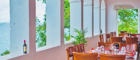 Un restaurante con terraza, columnas blancas y vista al mar.