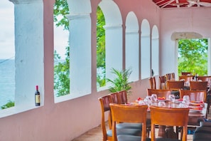 Un restaurante con terraza, columnas blancas y vista al mar.