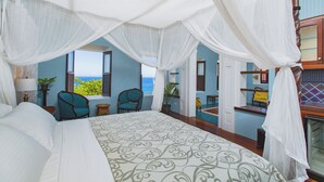 Une chambre avec un grand lit, une vue sur l’océan et un balcon équipé d’une chaise et d’une table.