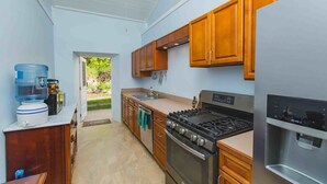 Une cuisine avec des meubles de rangement en bois, une cuisinière à gaz, un distributeur d’eau et un réfrigérateur.