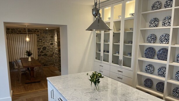 A kitchen with a marble countertop, a vase with a plant, and a cabinet with blue and white plates. - In Town Beautiful Trim Castle Cottage   (Trim)