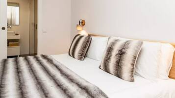 Habitación de hotel con cama, lámpara de noche, espejo y vista al baño.