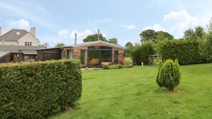 A two-story house with a visible front yard, a wooden deck, and a small garden area.