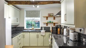 A kitchen with light-colored cabinets, a black countertop, and a window with a view of greenery outside.