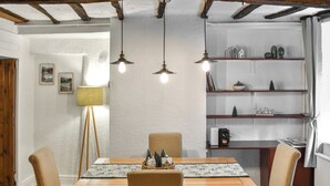 Un comedor con una mesa de madera, cuatro sillas y lámparas colgantes.
