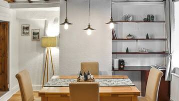 Un coin repas avec une table en bois, quatre chaises et des lampes suspendues.