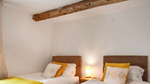 Una habitación con dos camas, cada una con cabecero y mesita de noche con lámpara.