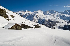 A snow-covered mountain village with stone buildings and a clear view of distant peaks. - HOTEL DU SOLEIL (Torgnon)