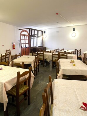 A dining area with multiple tables and chairs, a fire extinguisher, and a window with a wooden frame. - HOTEL DU SOLEIL (Torgnon)