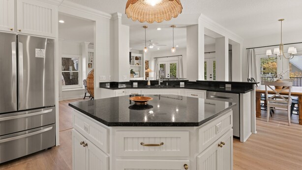 A spacious kitchen with white cabinetry, a central island, stainless steel appliances, and pendant lighting.