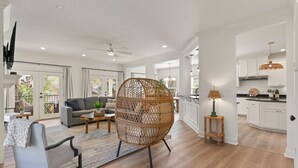 A spacious living room with a grey sofa, a wicker chair, and a coffee table.