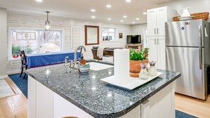 Une cuisine moderne dotée de plans de travail en granit, d’un réfrigérateur en acier inoxydable et d’un grand îlot central avec un évier.